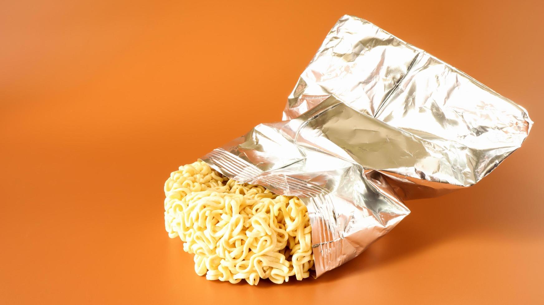 Raw dried instant noodles in open condition from an unnamed foil packaging without a name close-up on a yellow background. pasta, for the preparation of which it is enough to pour water photo