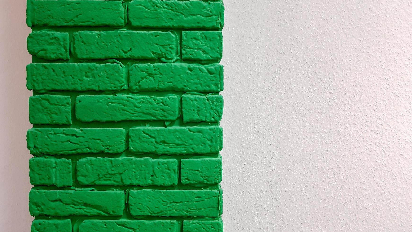 Modern new flat pink wall with a decorative brick column painted green. Abstract modern trendy texture background. Copy space empty space for your text and advertisement. photo