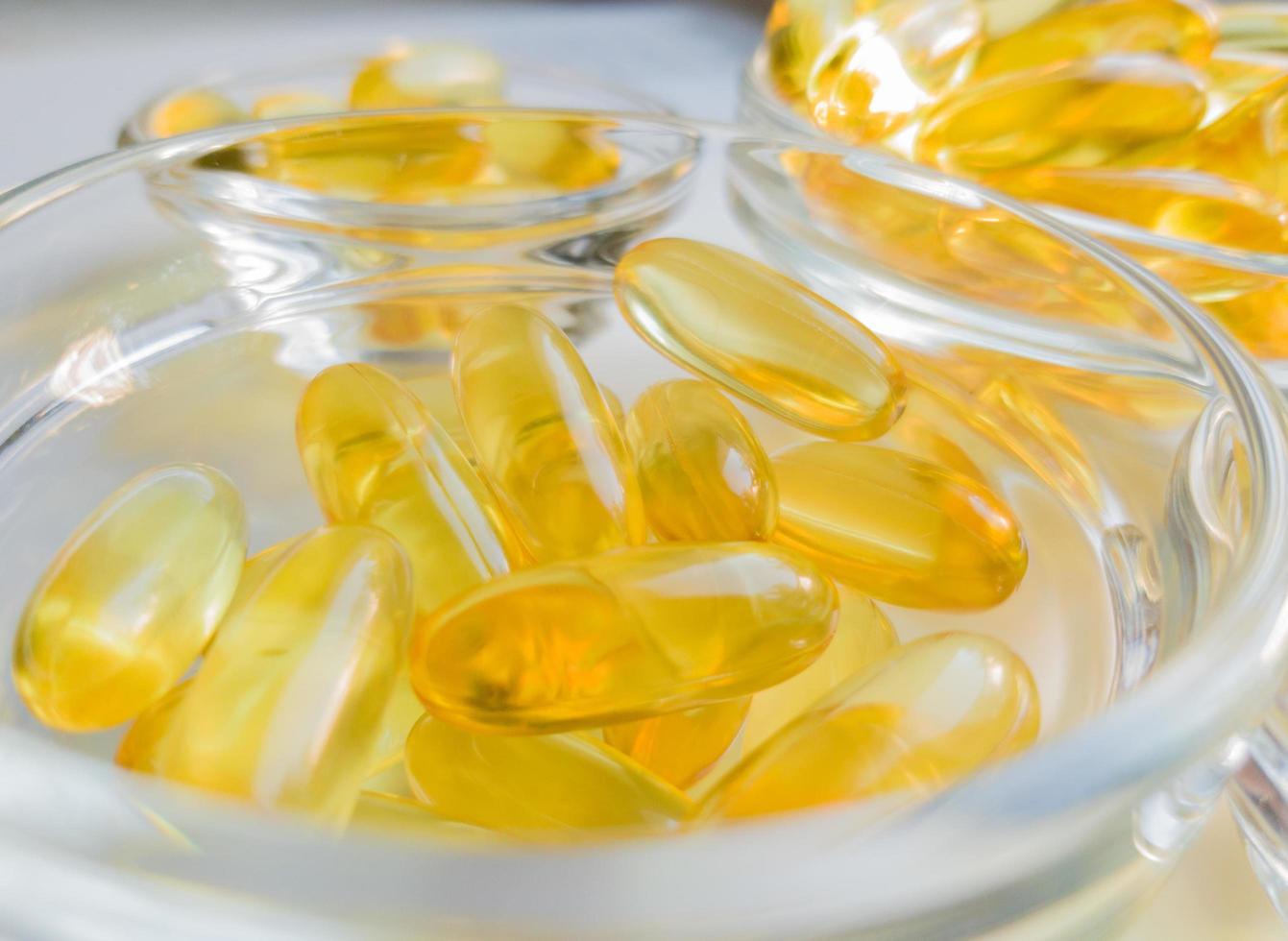 cápsulas de aceite de pescado en una placa de vidrio. mucha vitamina omega 3 en un fondo blanco. primer plano, vista superior, producto de alta resolución. metabolismo en el cuerpo. el cuerpo de calcio. una manera rapida de perder peso foto