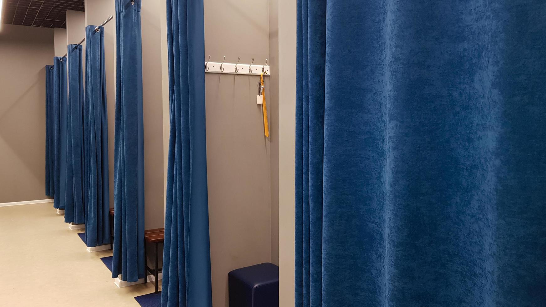 Boutique interior, fitting room in a shopping center. Nobody. Empty fitting rooms with blue curtains and gray walls and a large mirror. Dressing rooms in a clothing store without people. photo