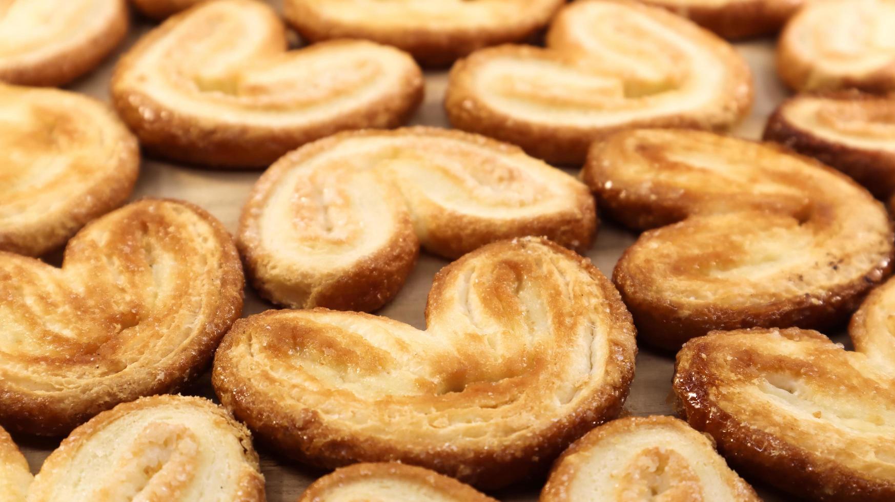 Fresh puff pastry palm cookies in the shape of a heart. Classic French pastries. Pig ear, elephant ear cookies, French hearts. View from above photo