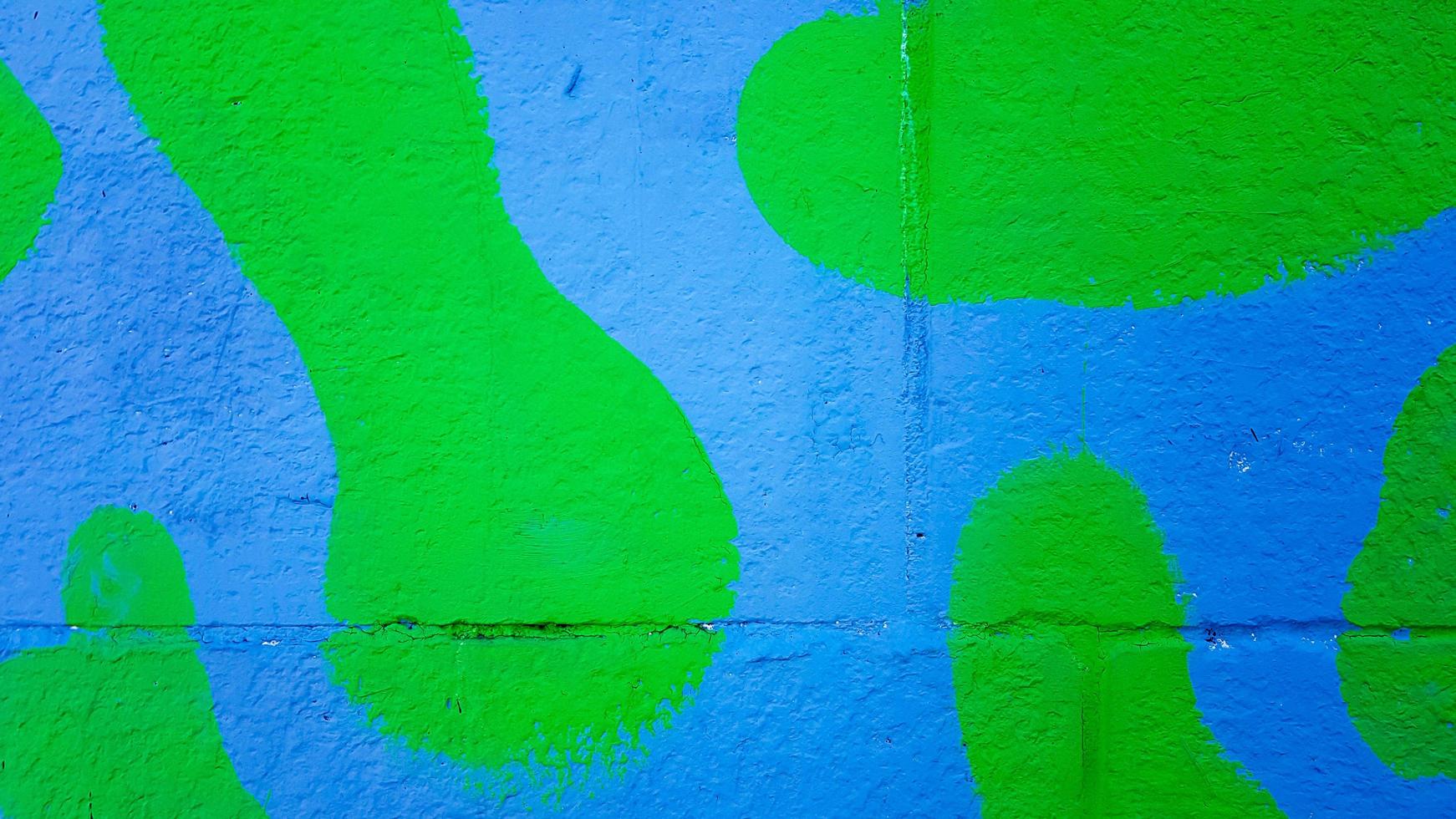 The concrete wall is painted in green and blue camouflage. Stains of paint on a stone wall, colorful background with copy space. photo