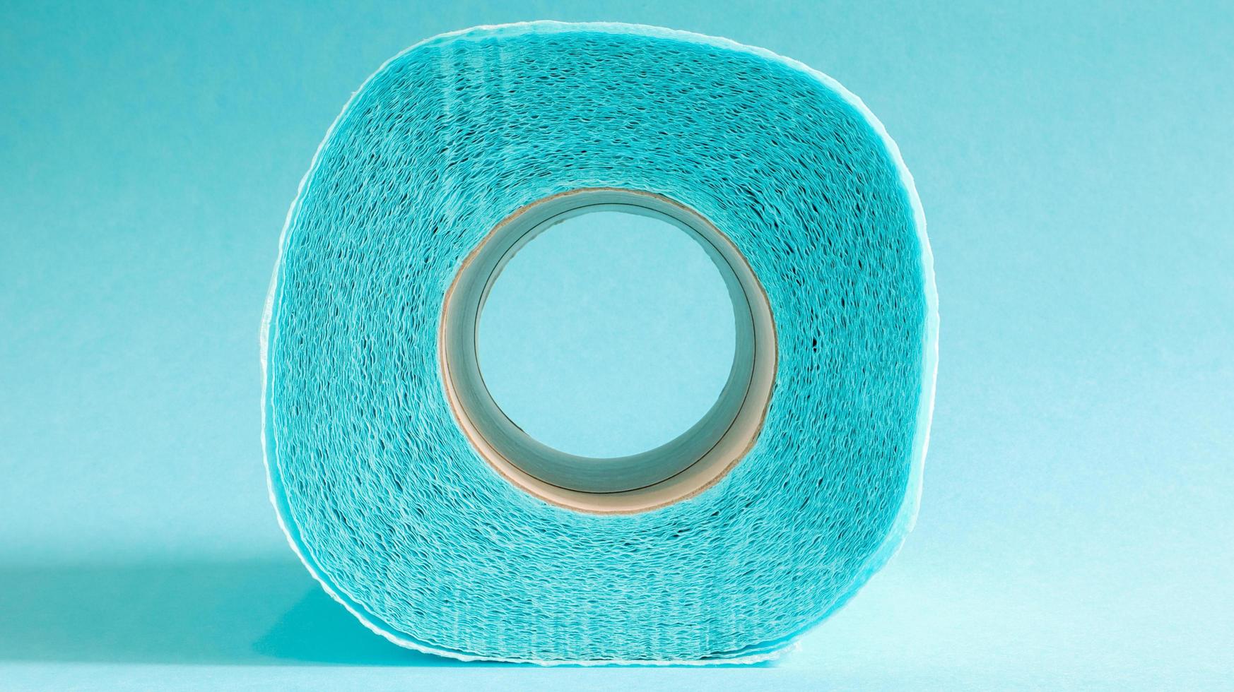 Blue roll of modern toilet paper on a blue background. A paper product on a cardboard sleeve, used for sanitary purposes from cellulose with cutouts for easy tearing. Embossed drawing photo