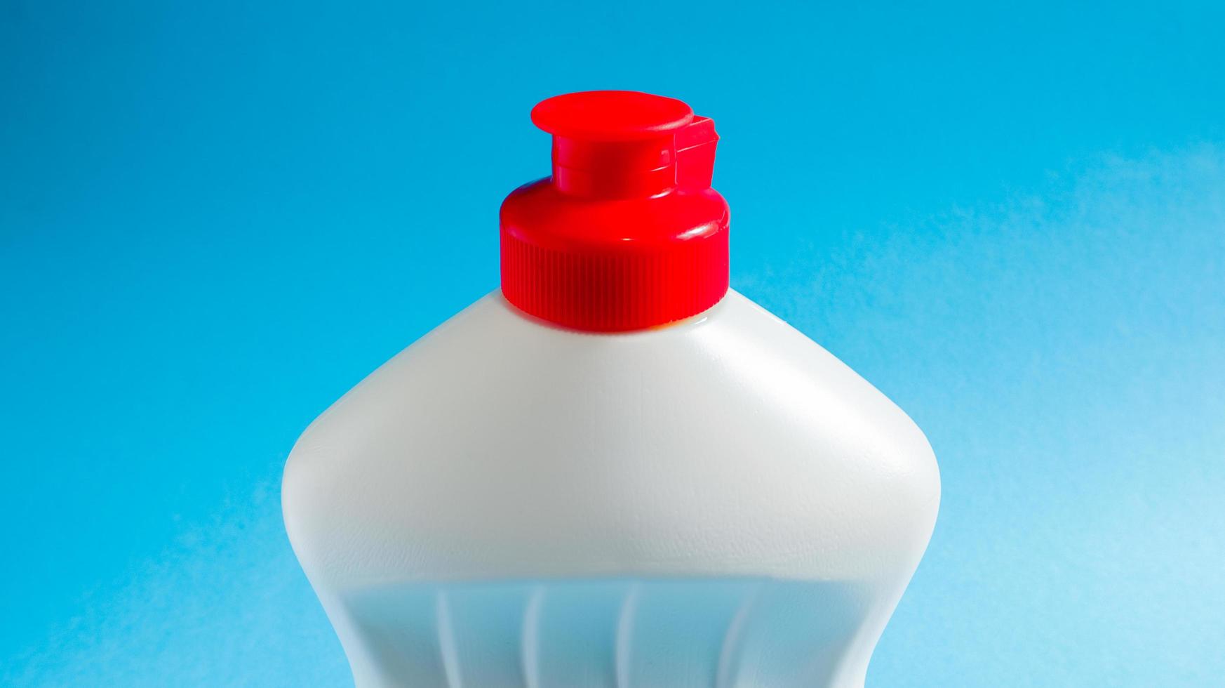 White plastic bottle with dishwashing detergent, bleach or fabric softener on a blue background. liquid washing powder. The concept of cleaning. photo