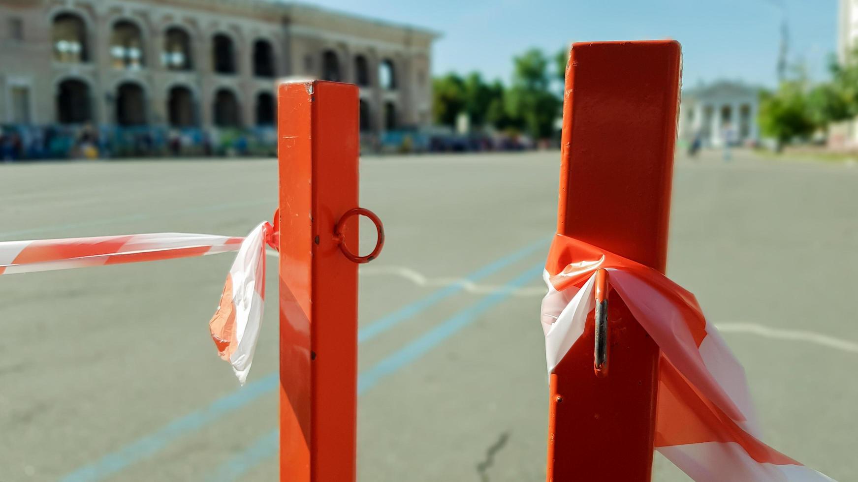 Red white does not cross the tape and the metal pole. Signal red and white tape hanging on a metal fence, danger, warning. Ribbon and metal red post. Forbidden tape encloses an unsafe area. photo