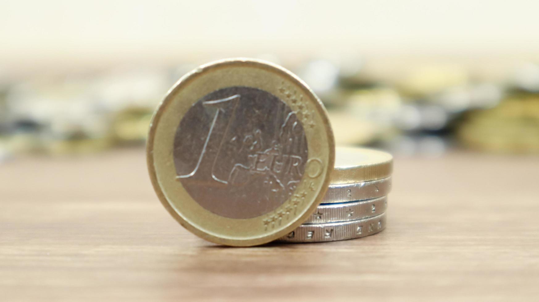 Close-up of one euro coin on the desktop. European metallic cash and in the background euro cents coins are out of focus. photo