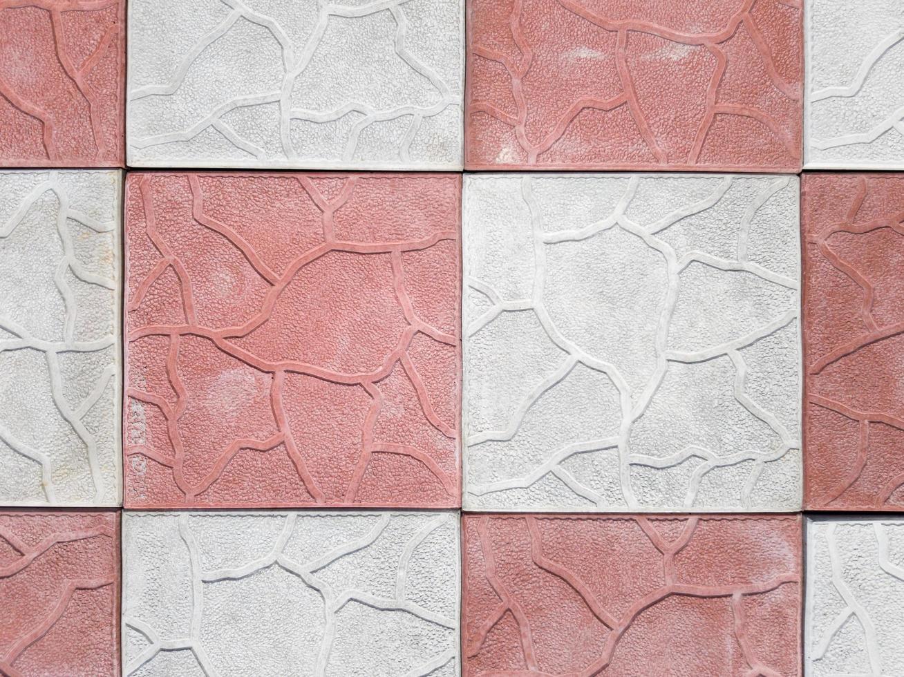 concrete coating of gray and red colors. Sidewalk of gray and pink pavers close-up. Texture, background from curly gray-orange stone. Top view on the sidewalk photo