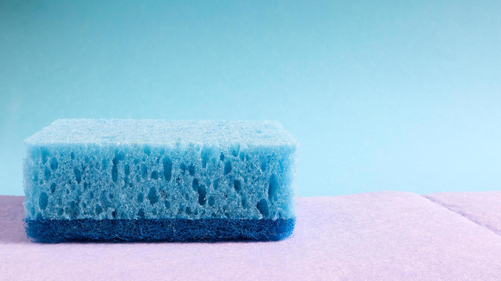 una esponja azul usada para lavar y borrar la suciedad que usan las amas de casa en la vida cotidiana. están hechos de material poroso como la espuma. retención de detergente, que te permite gastarlo económicamente foto
