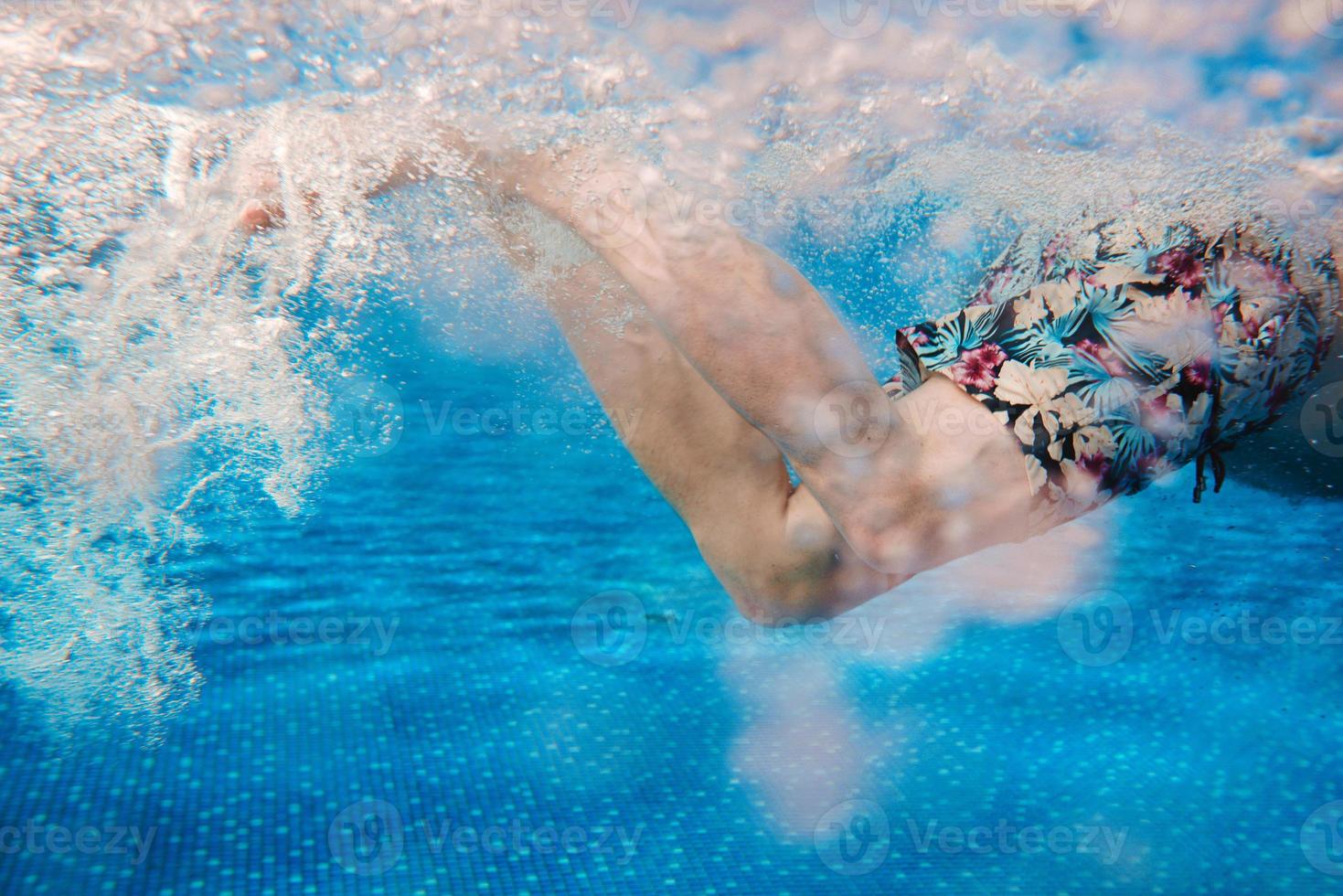 piernas de hombres nadando bajo el agua en la piscina en verano foto
