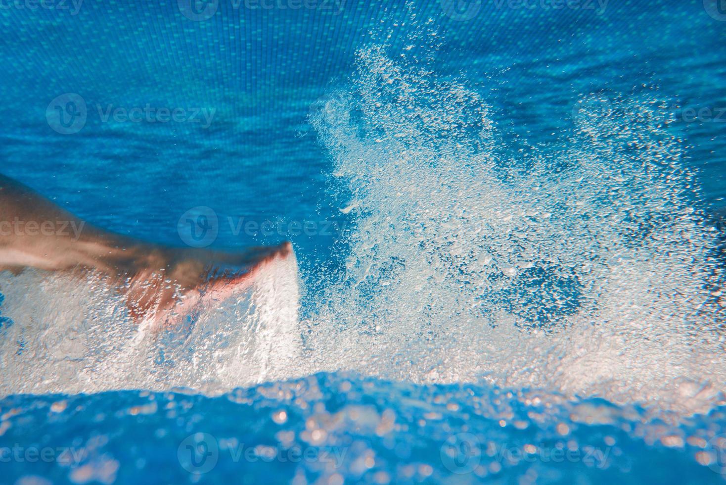 piernas de hombres nadando bajo el agua en la piscina en verano foto