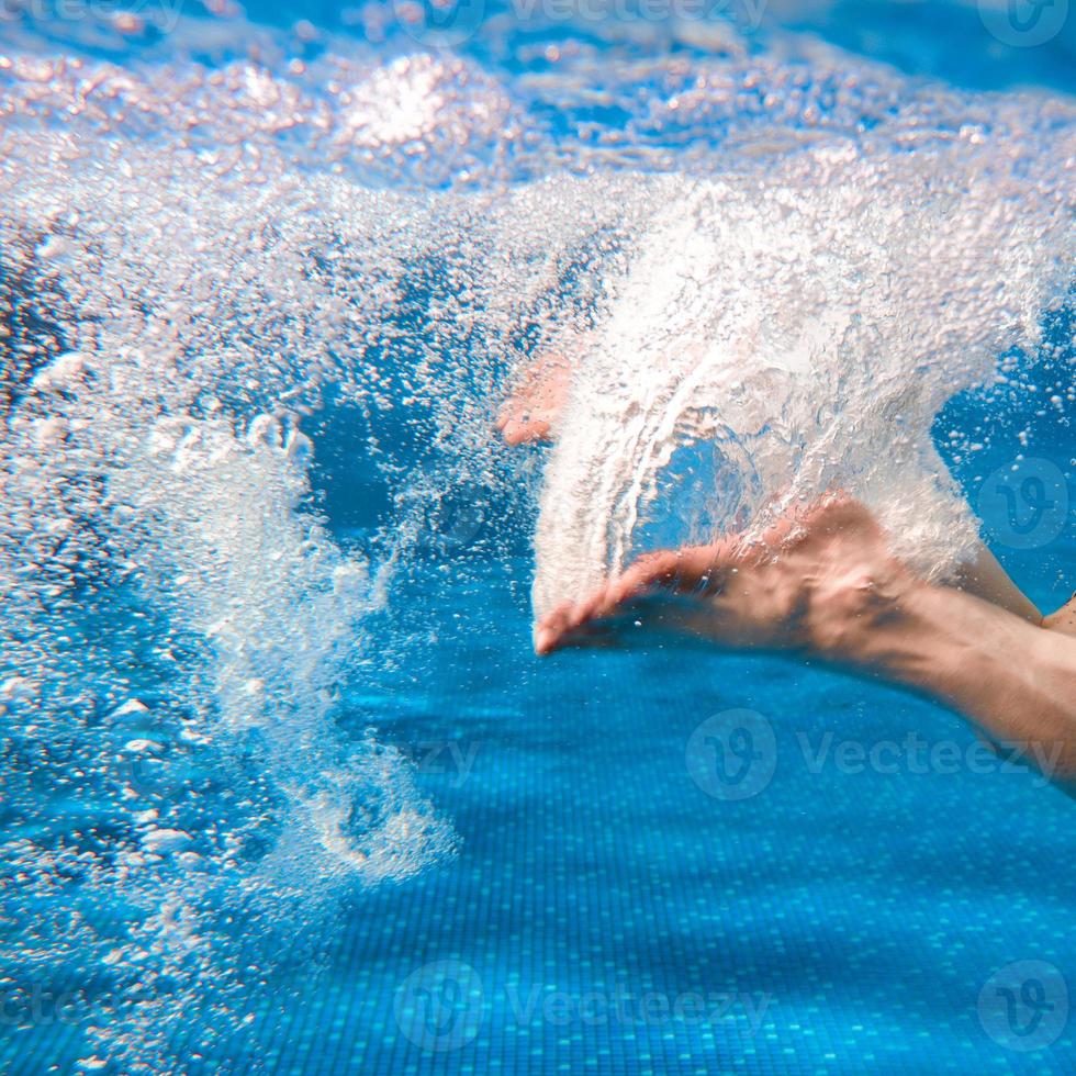 piernas de hombres nadando bajo el agua en la piscina en verano foto