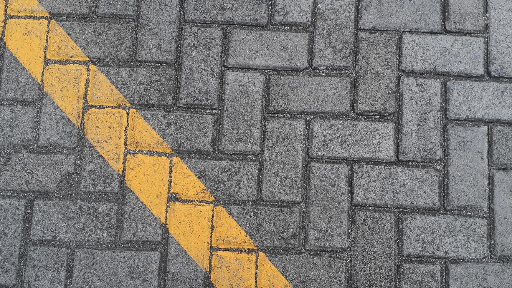 Paving slab gray urban street with diagonal yellow lines road markings stone tile texture background photo