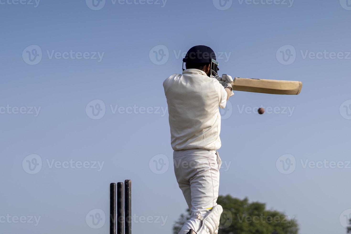 un jugador de críquet jugando al cricket en el campo vestido de blanco para los partidos de prueba. deportista golpeando un tiro en la pelota de cricket. foto