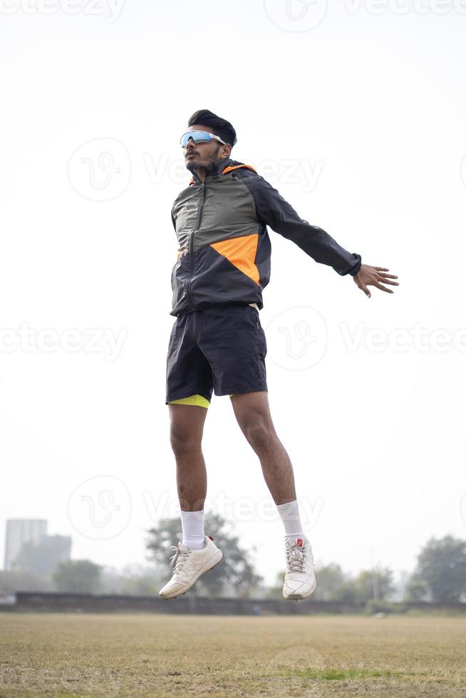 Sports and lifestyle concept- Young boy jumping on the field. Indian sportsman exercising in the field. photo