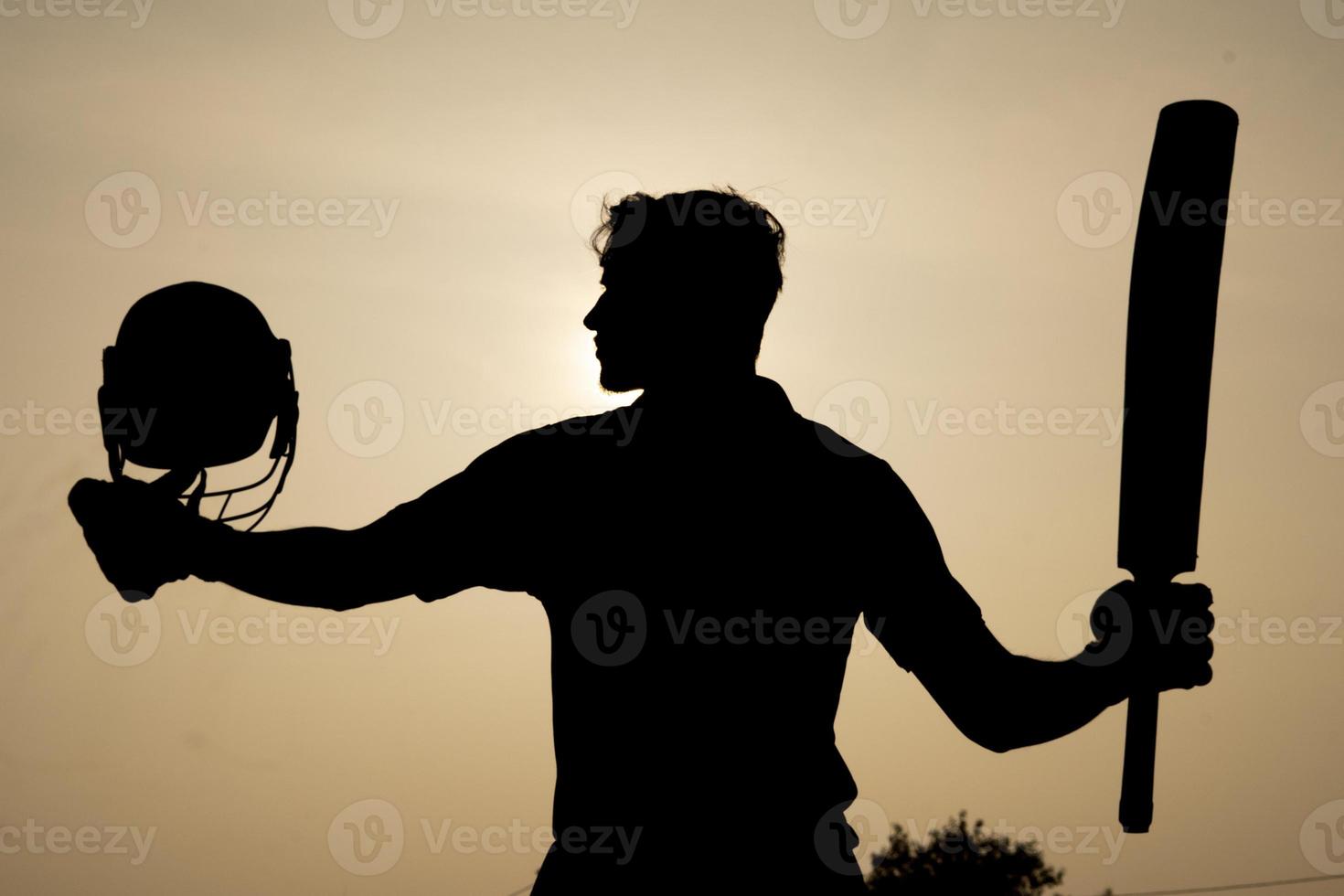 Silhouette of a cricketer celebrating after getting a century in the cricket match. Indian cricket players and sports concept. photo