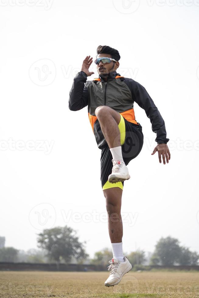 joven indio haciendo ejercicio y saltando en el campo de deportes. concepto de estilo de vida saludable y deportivo. foto