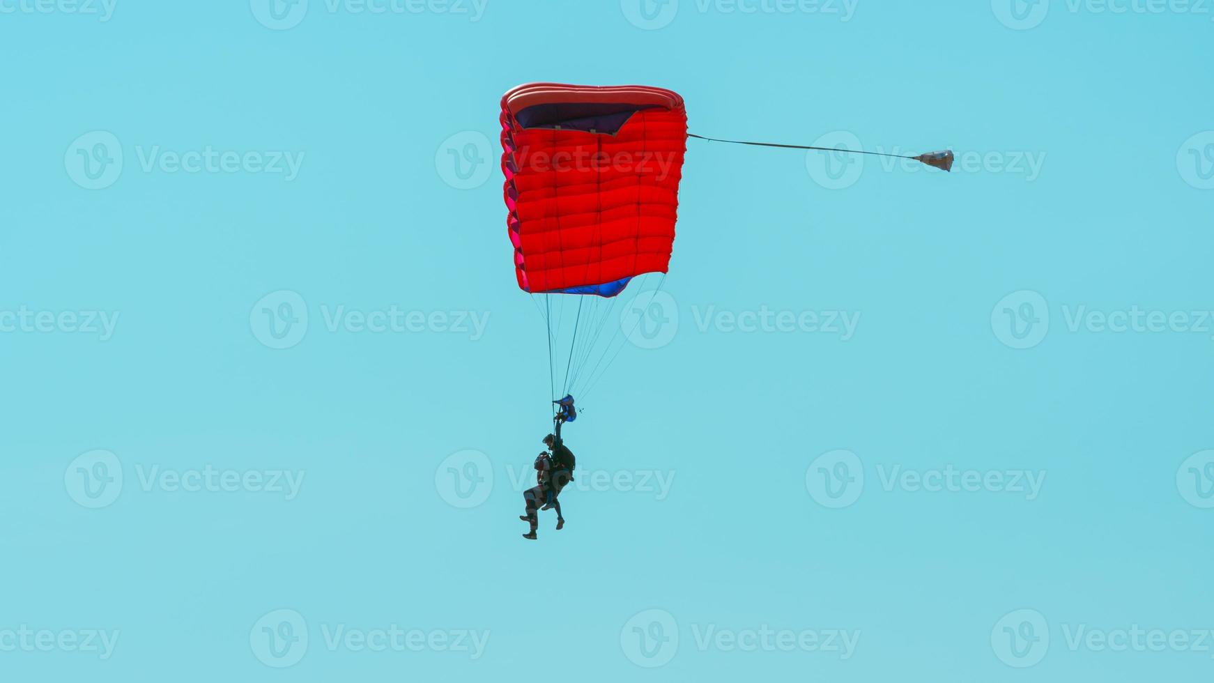 Tandem parachute jump. Silhouette of skydiver flying in blue clear sky. photo
