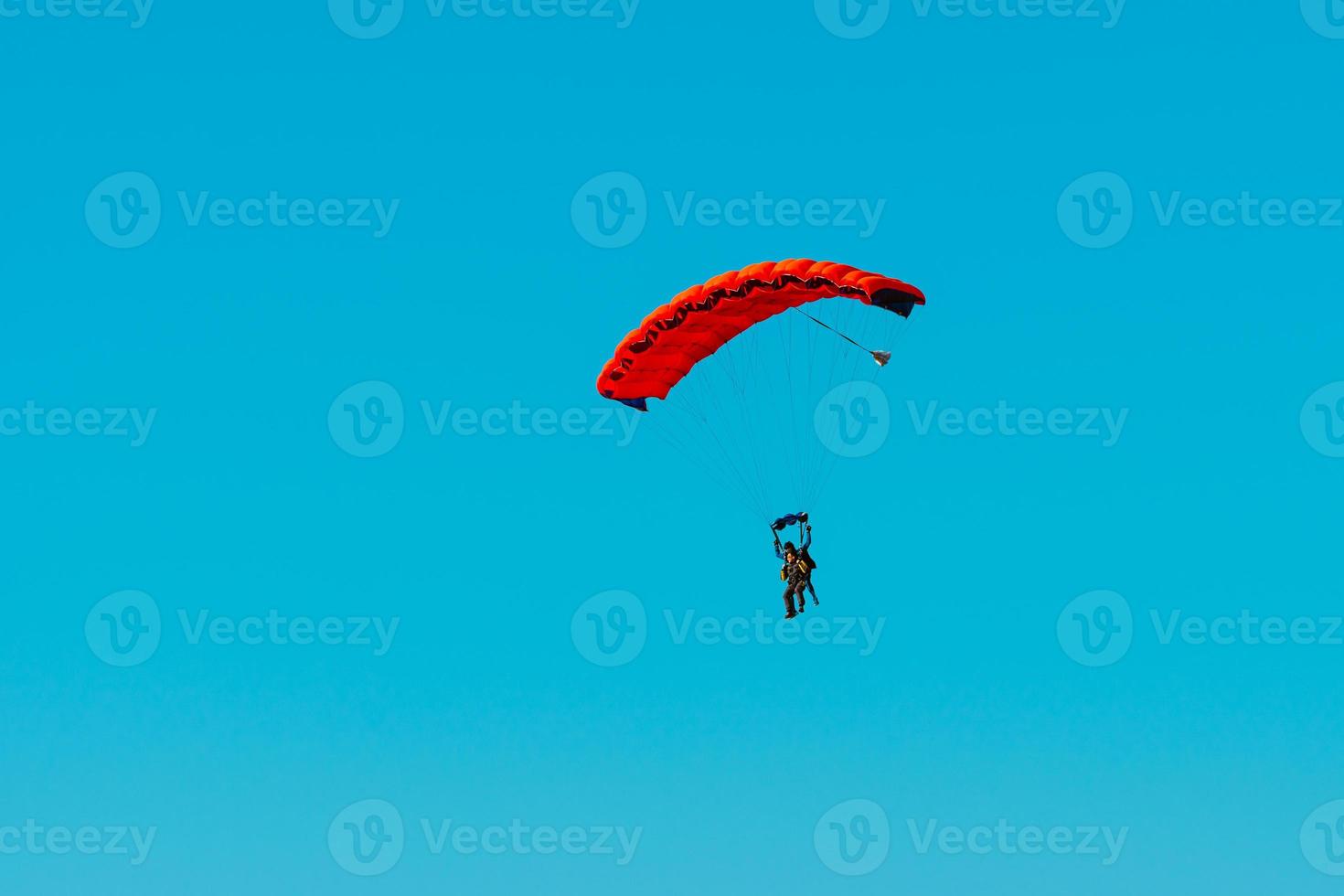 Tandem parachute jump. Silhouette of skydiver flying in blue clear sky. photo