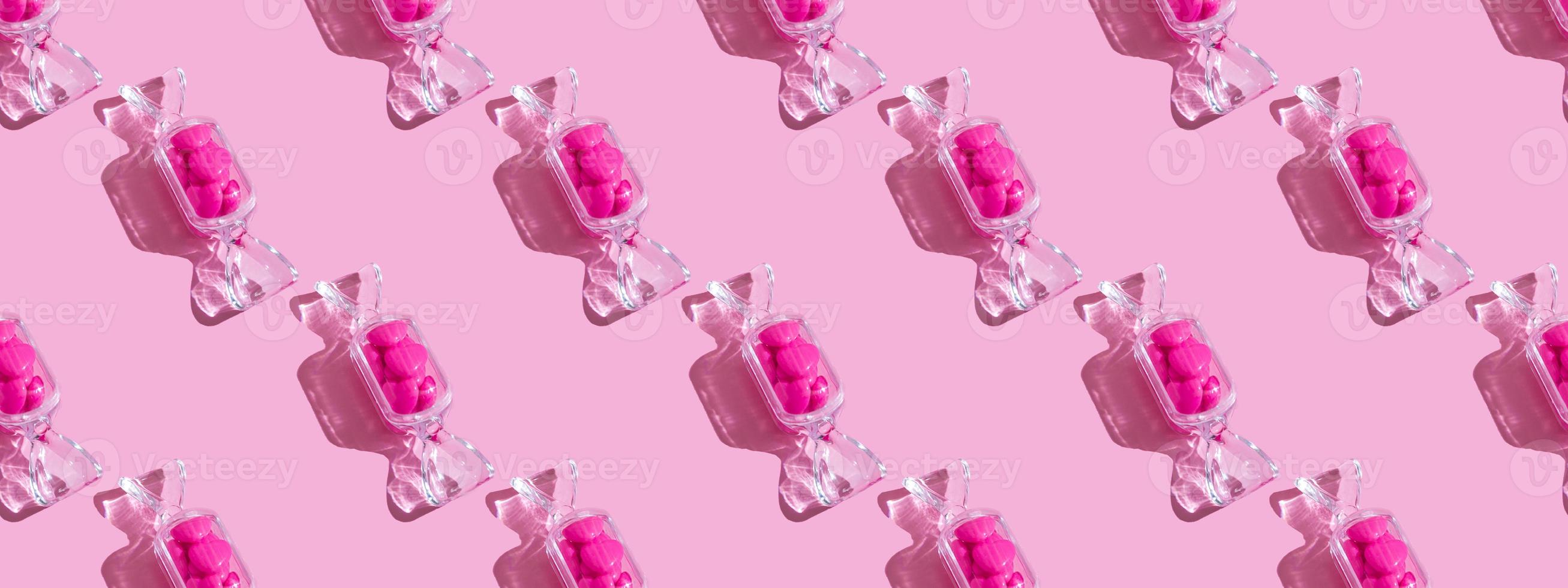 caja transparente en forma de caramelo con piruletas de corazón dulce con sombra dura sobre fondo rosa con espacio para copiar. el concepto de día de san valentín, día de la madre. patrón foto