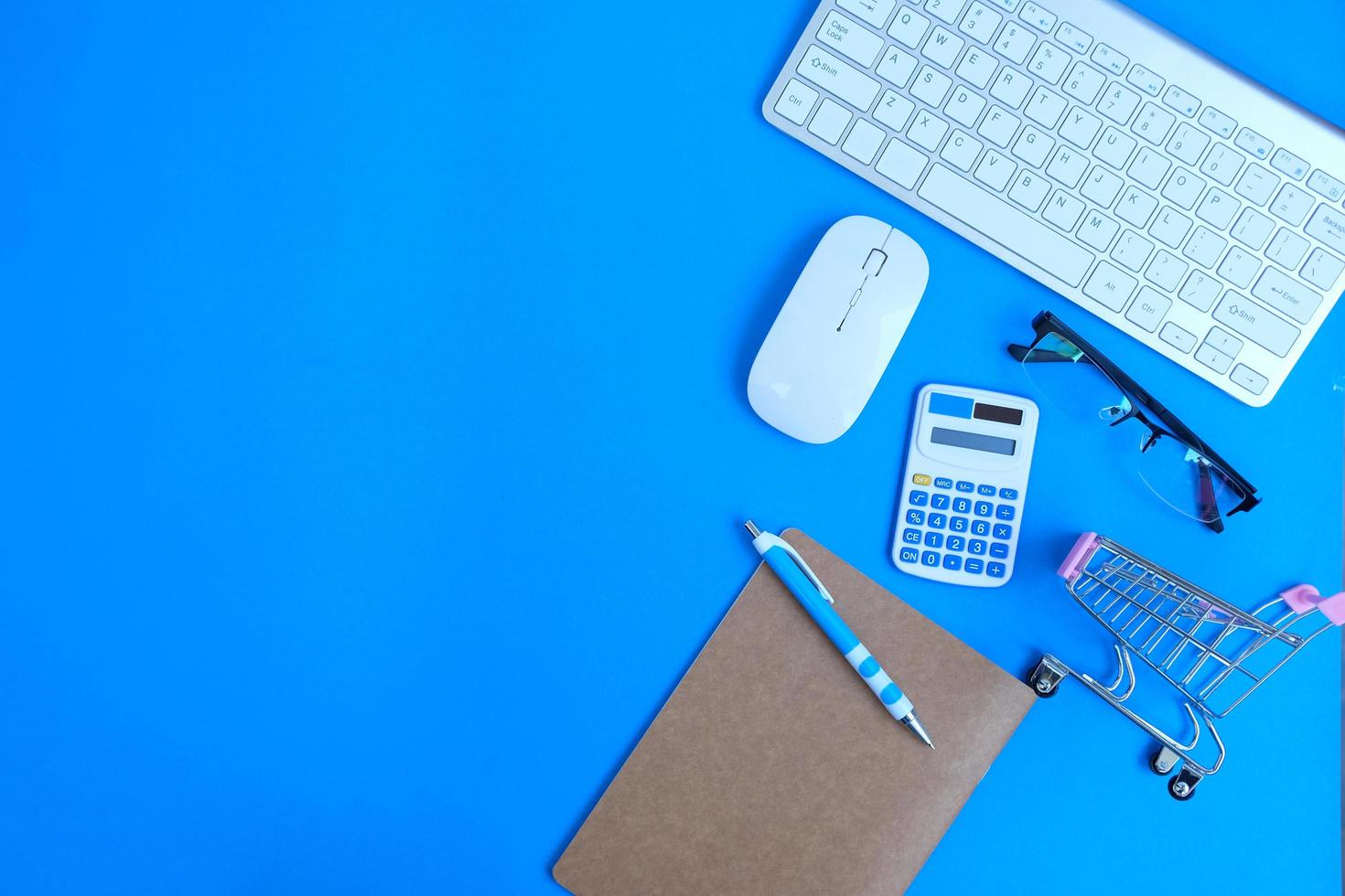 Office desk table with computer tools and supplies is a blank notebook with a pen. Flat lay, top view with copy space. photo