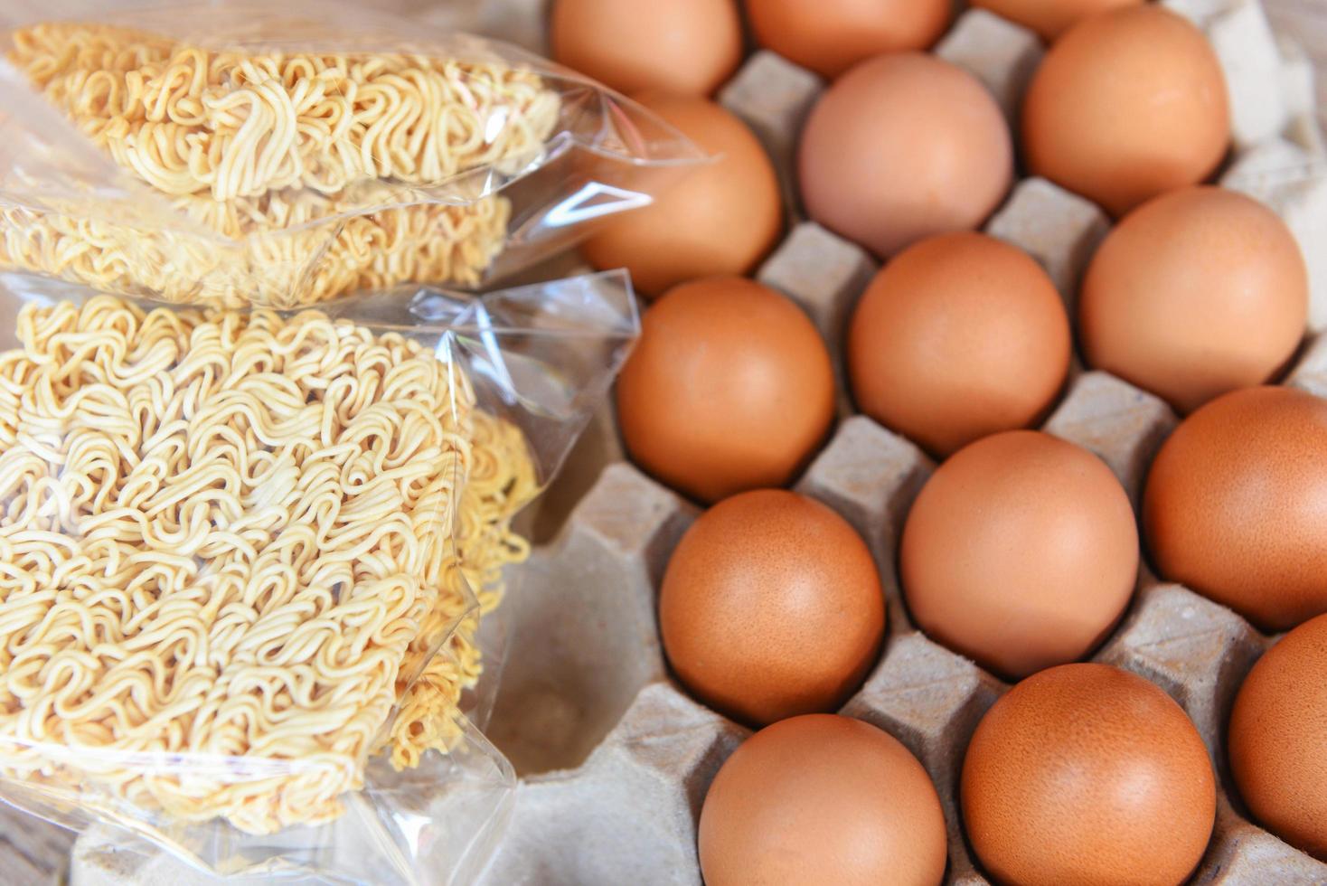 instant noodles and eggs in egg box on background - set of dry food non perishable storage goods in kitchen home or for donations photo