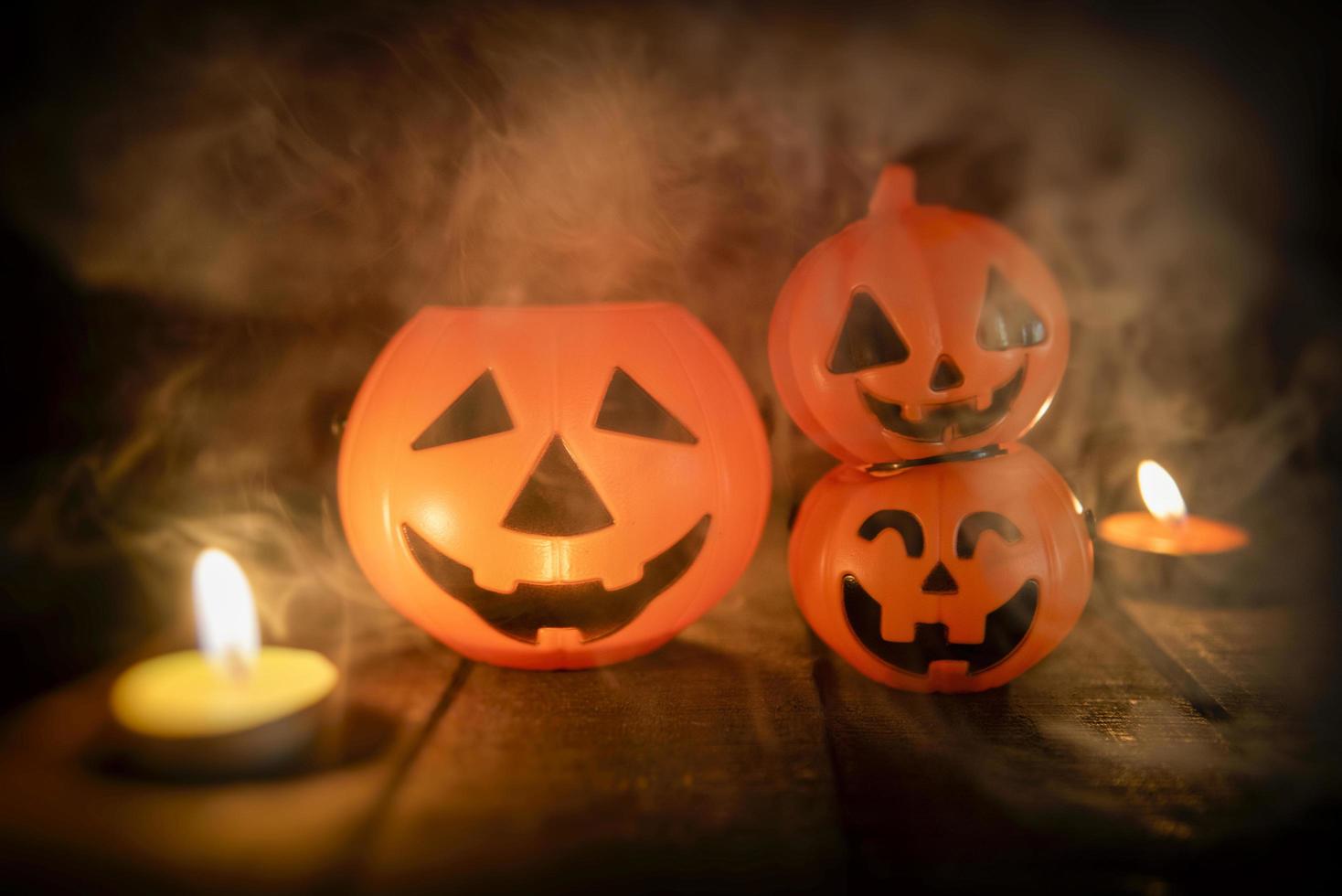 Halloween pumpkin lantern candle light on wooden with smoke - head jack o lantern funny faces spooky holiday decorate on halloween background photo