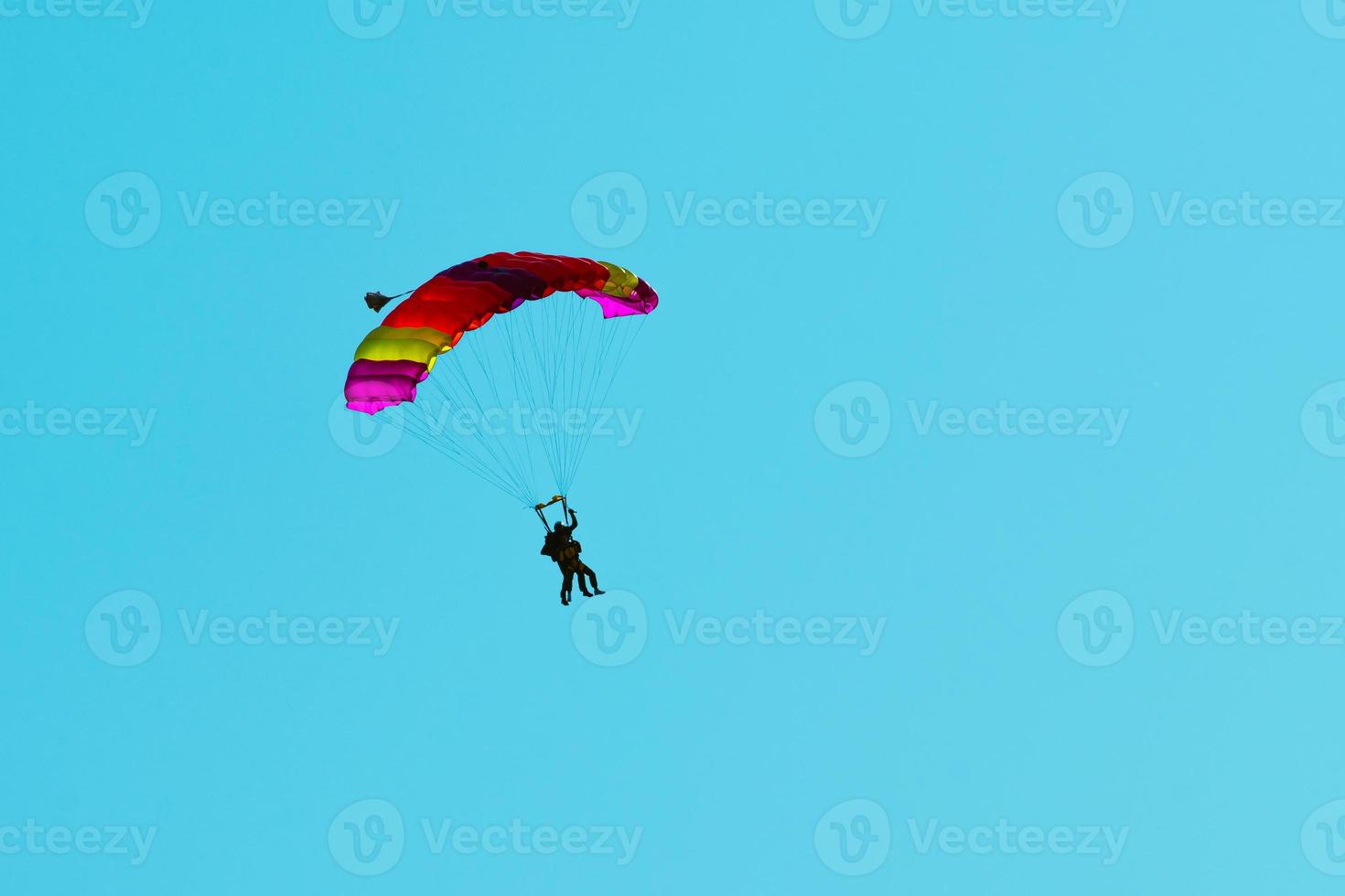 salto en paracaídas en tándem. silueta de paracaidista volando en un cielo azul claro. foto