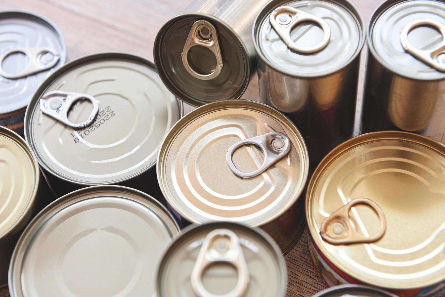 Various canned food in metal cans on wooden background , top view - canned goods non perishable food storage goods in kitchen home or for donations photo