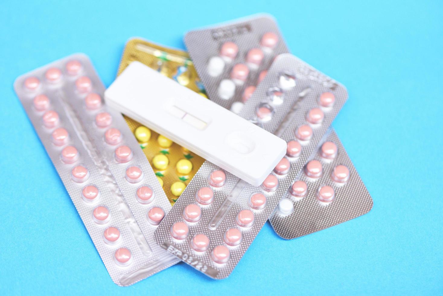 Contraception pills and Pregnancy test on blue background - Birth control contraceptive means prevent pregnancy photo