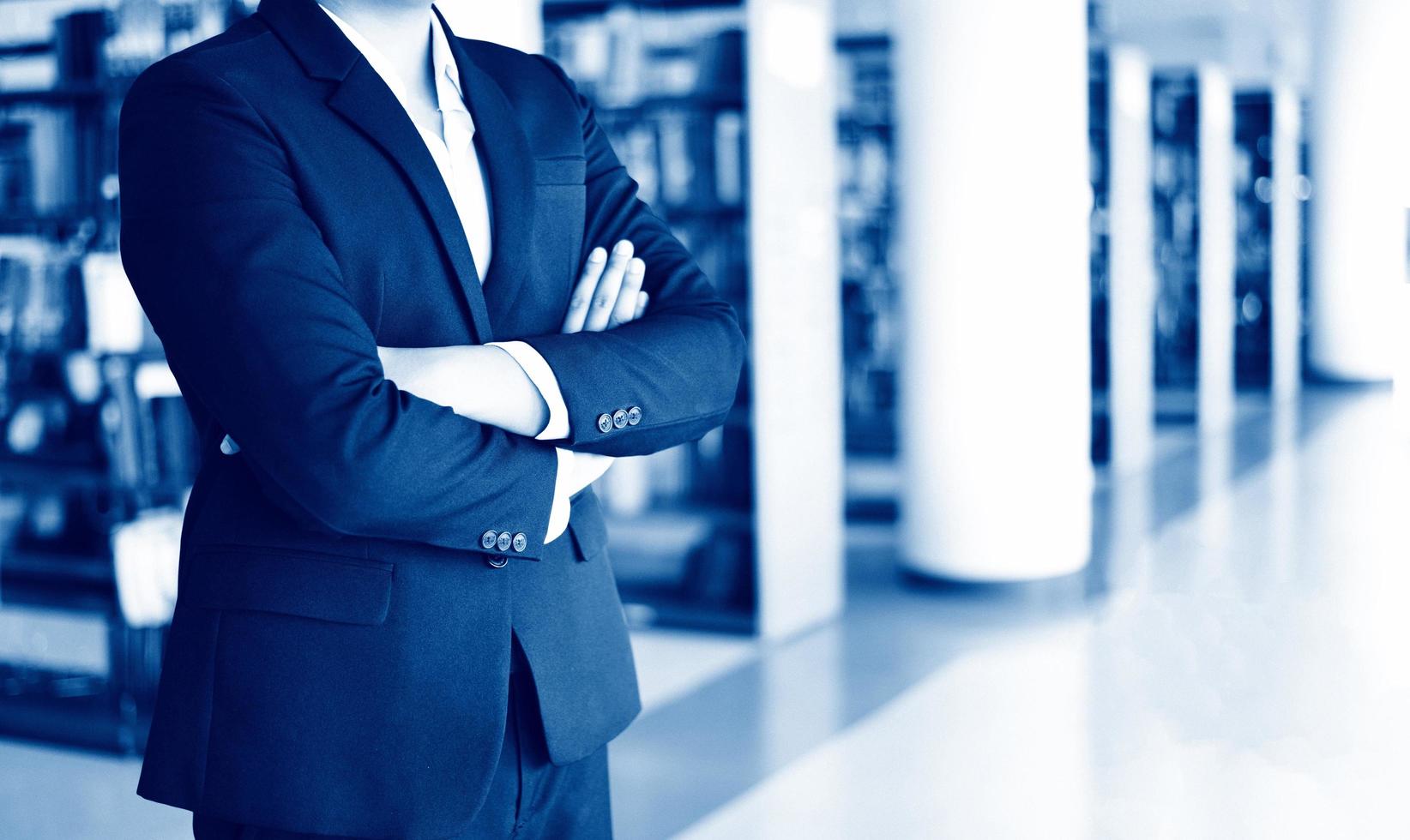 businessman standing in a office - smart business man or student standing in the library room with bookshelf background people business education concept photo