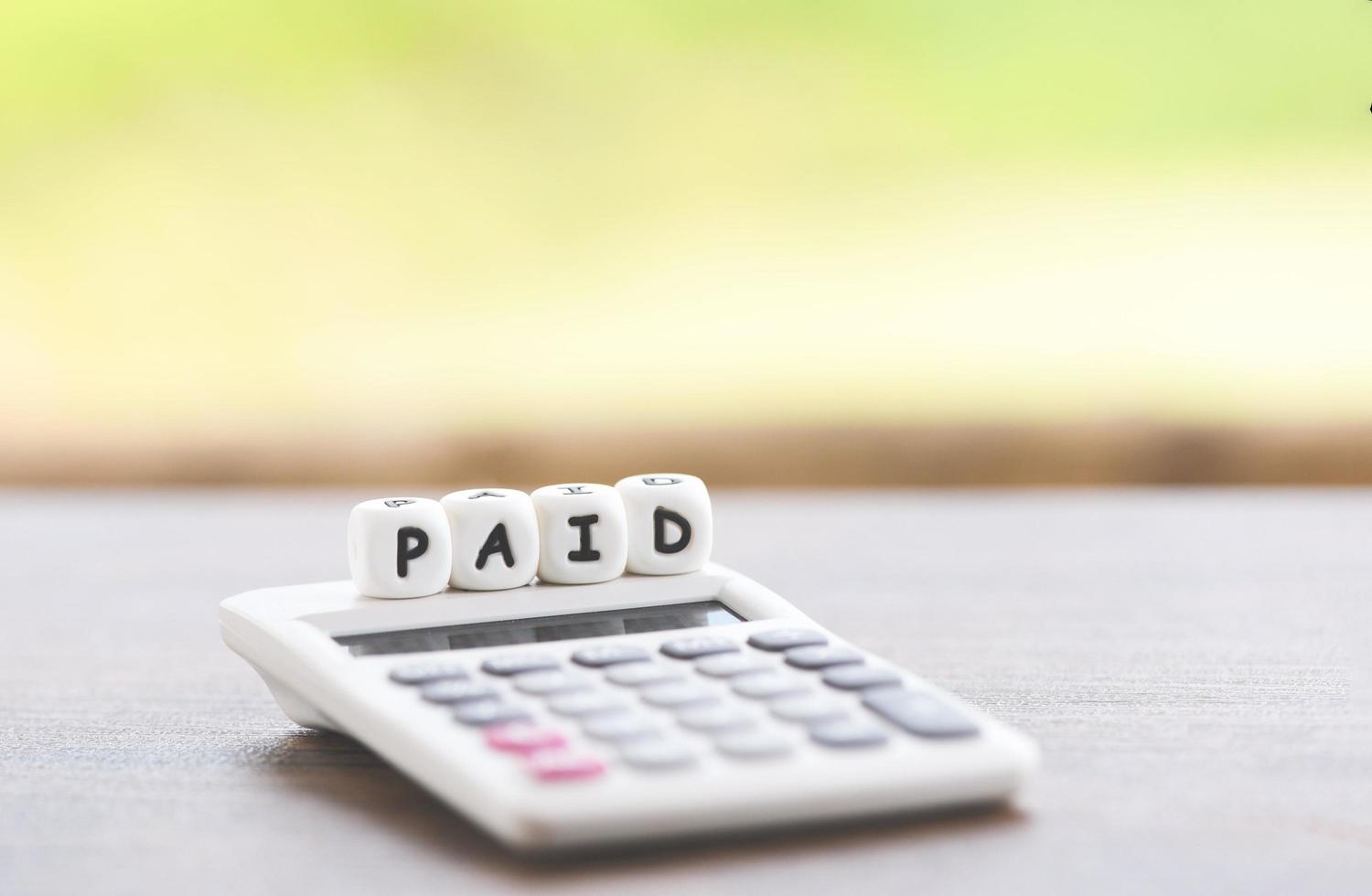 Paid words and calculator on table for time paid payment at office business photo