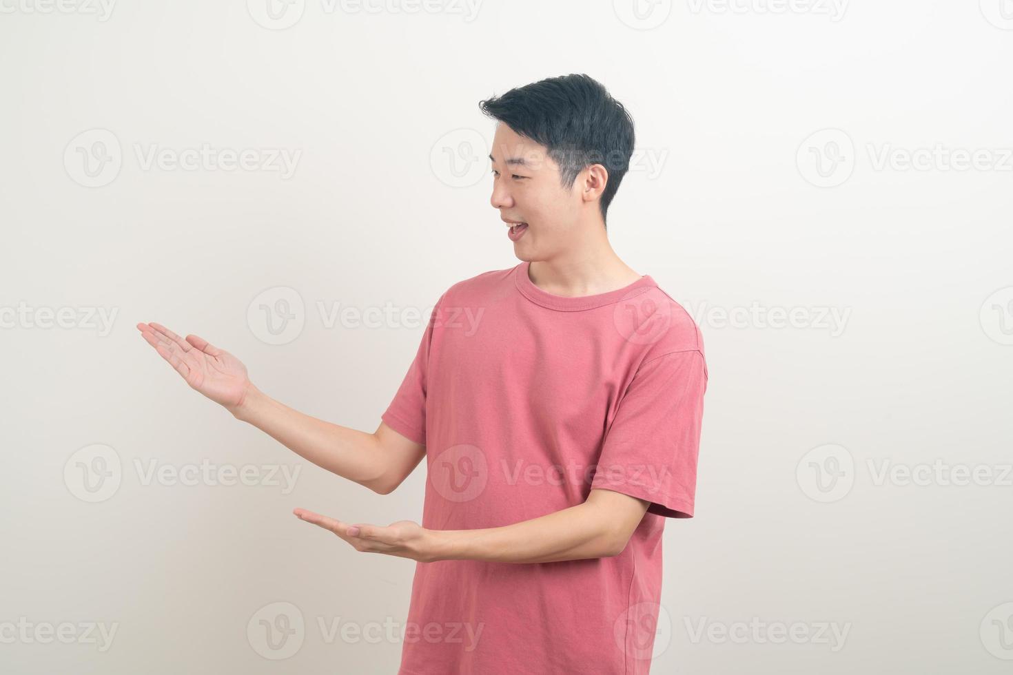 Hombre asiático con la mano apuntando o presentando sobre fondo blanco. foto
