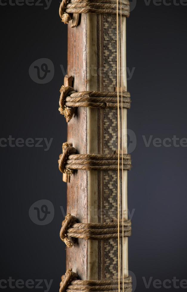 antiguo instrumento musical de cuerda asiático sobre fondo negro con retroiluminación. clavija de afinación foto