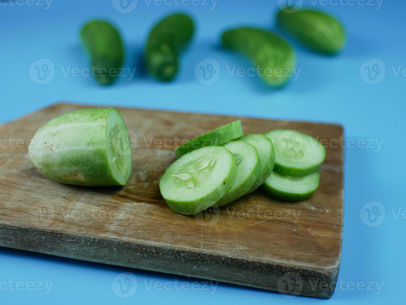 sliced cucumber on wooden cutting board with a blue background. healthy diet food concept photo