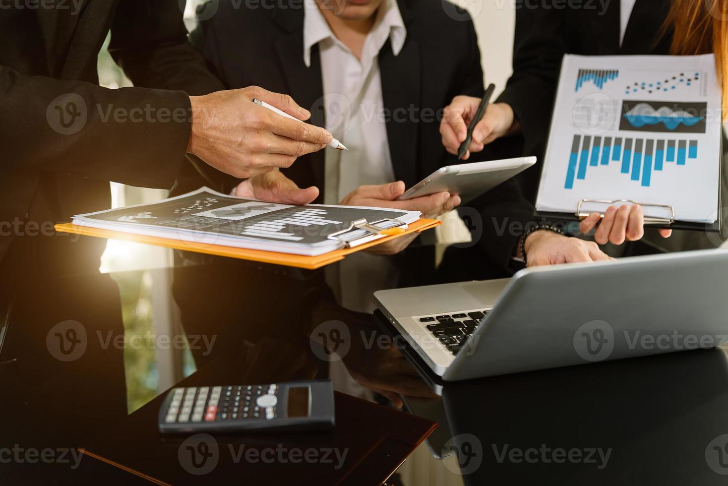 socios comerciales discutiendo documentos e ideas con teléfonos inteligentes y tabletas digitales y gráficos de negocios en la reunión de trabajo de un nuevo proyecto de puesta en marcha. foto