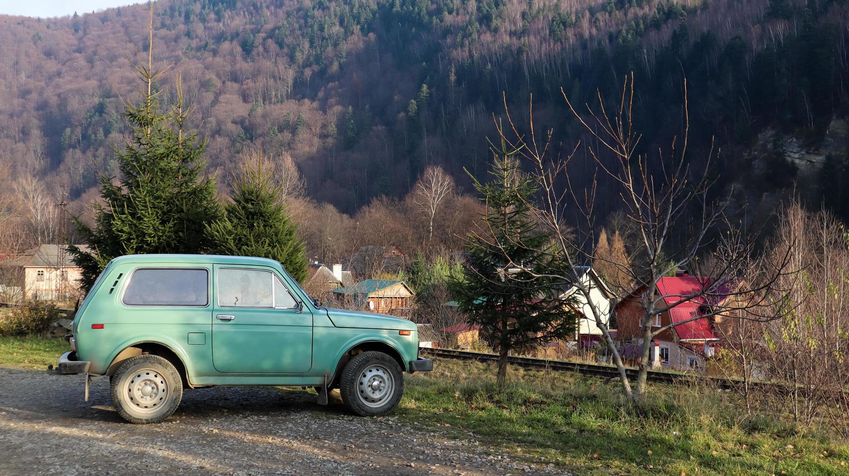 Ucrania, Yaremche - 20 de noviembre de 2019. Un jeep está estacionado con una cordillera al fondo. el coche está en las montañas de los cárpatos ucranianos en la pequeña ciudad de yaremche. foto