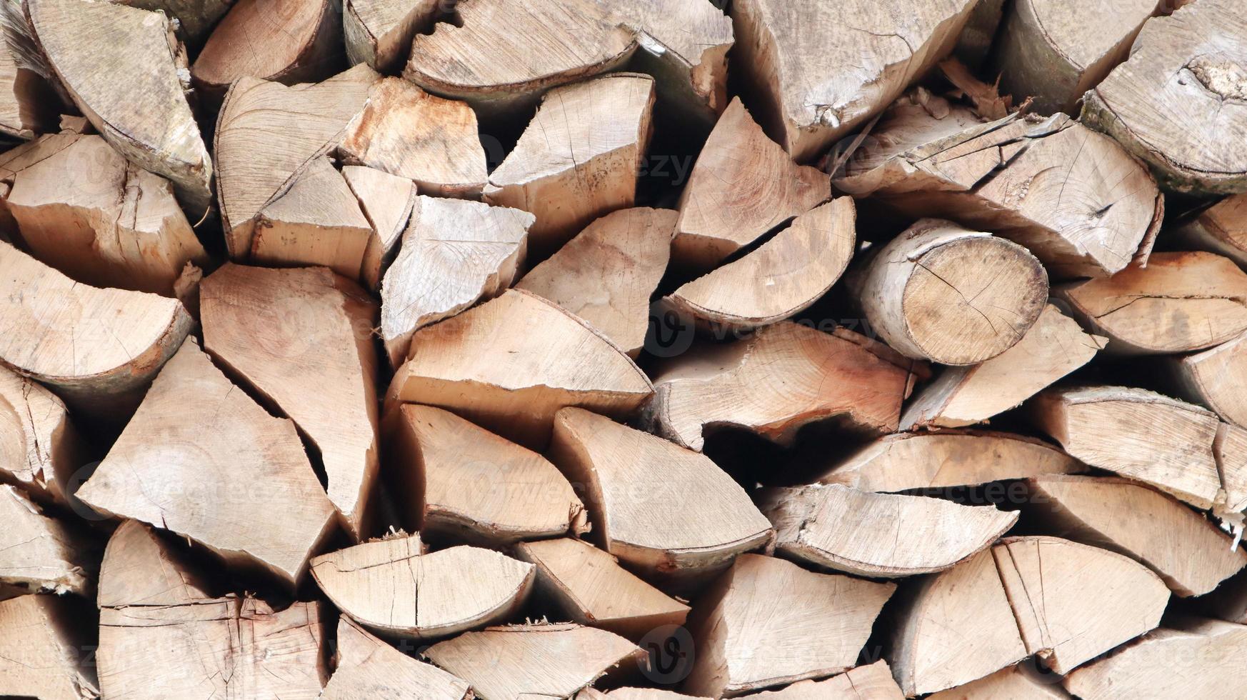 A neatly folded log of chopped wood. The fire is melting. Firewood stacked on top of each other. Firewood is collected for heating in cold weather. Background texture of stacked dry firewoods photo