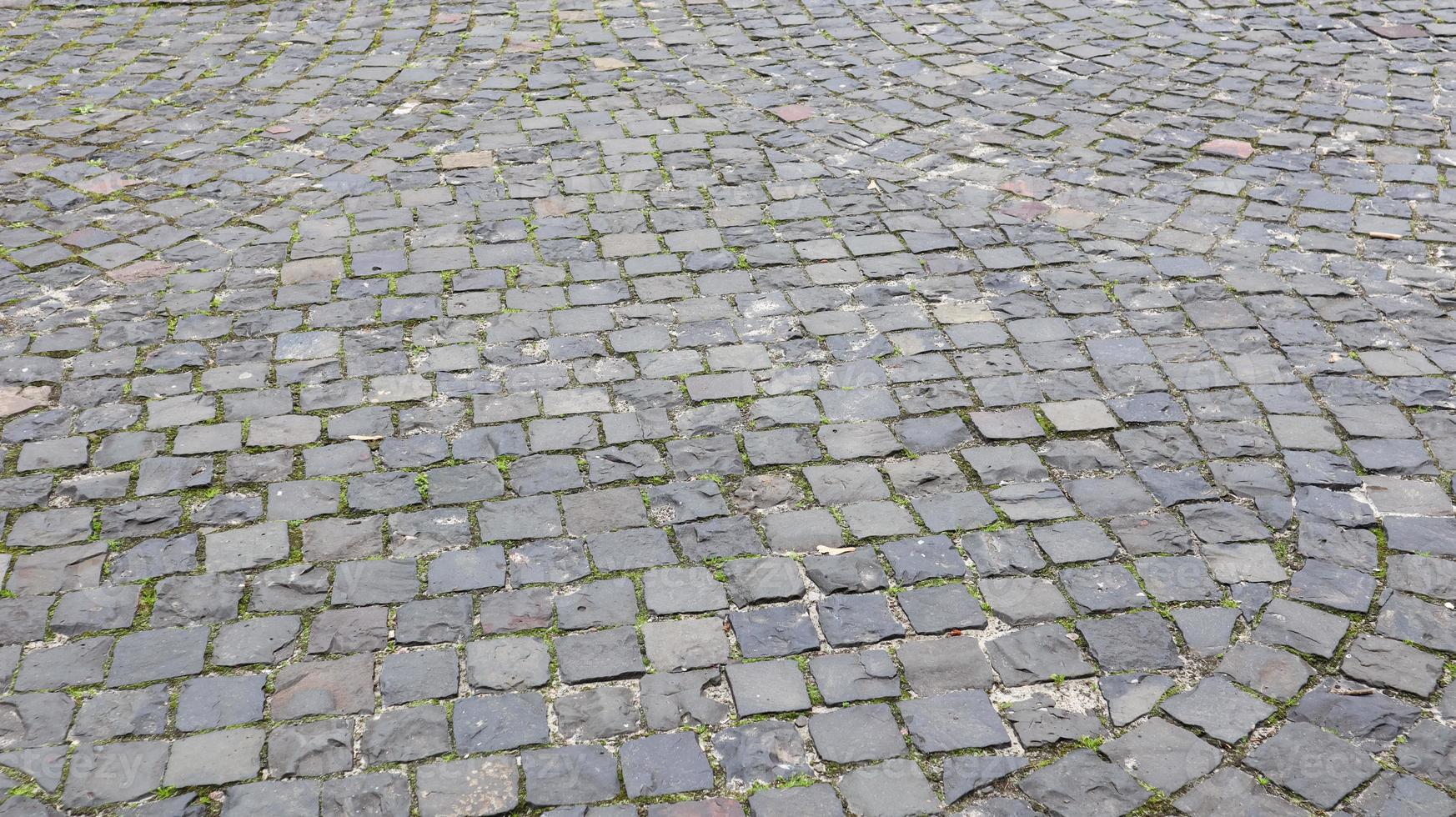 Side view of the cobblestones of the street. Detailed photo of the road surface. Traditional artwork on roads and sidewalks in the old part of the city.