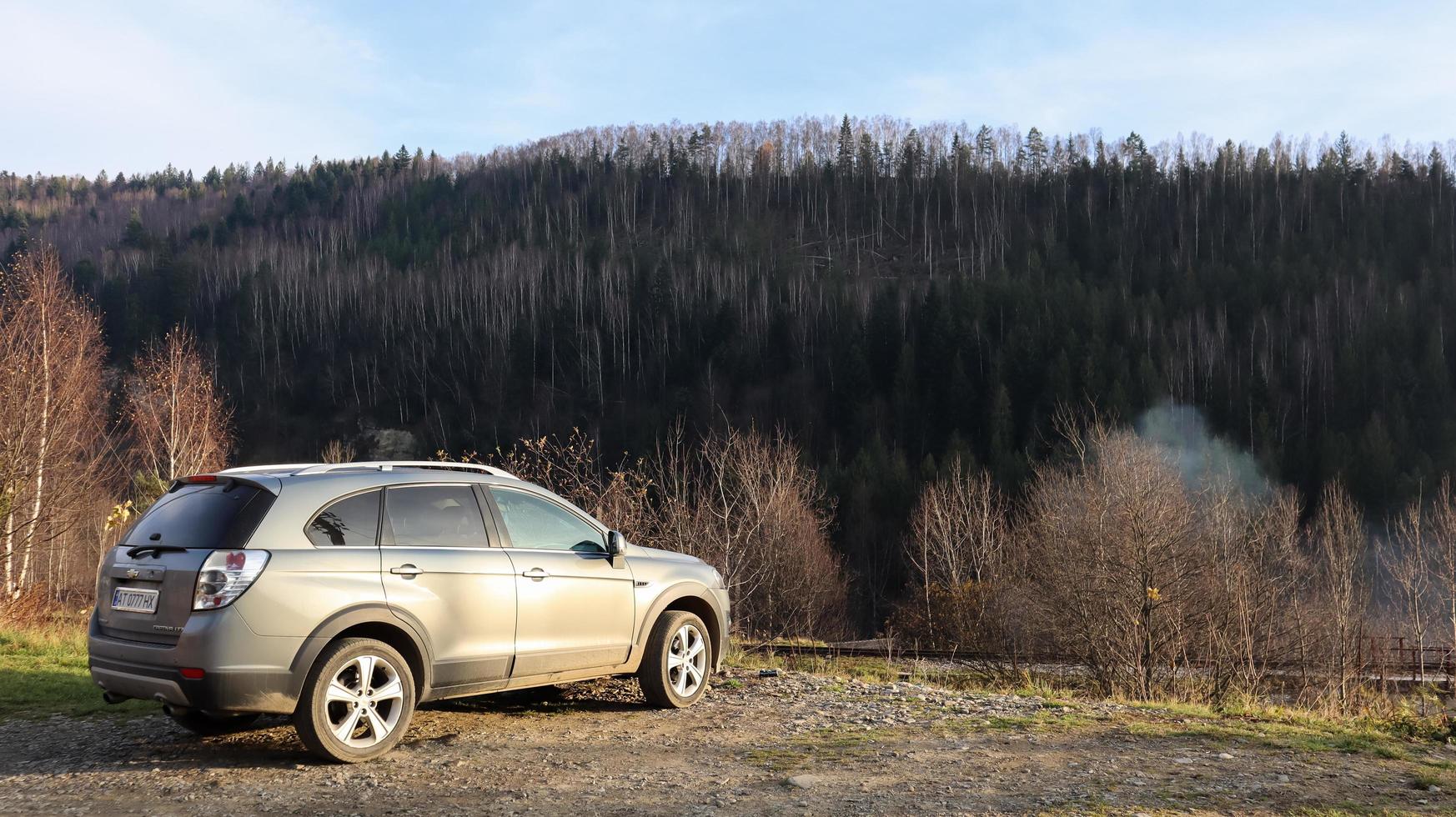 Ucrania, Yaremche - 20 de noviembre de 2019. Un jeep está estacionado con una cordillera al fondo. el coche está en las montañas de los cárpatos ucranianos en la pequeña ciudad de yaremche. foto