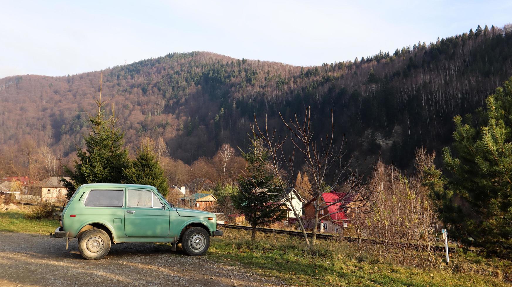 Ucrania, Yaremche - 20 de noviembre de 2019. Un jeep está estacionado con una cordillera al fondo. el coche está en las montañas de los cárpatos ucranianos en la pequeña ciudad de yaremche. foto