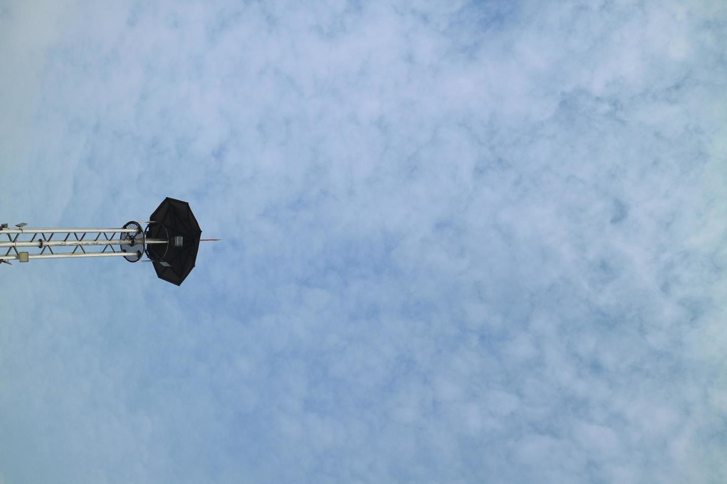 a high lamppost under a bright cloud photo