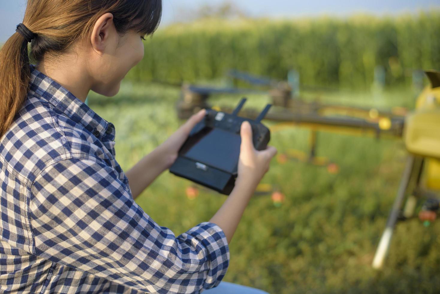 Young smart farmer controlling drone spraying fertilizer and pesticide over farmland,High technology innovations and smart farming photo