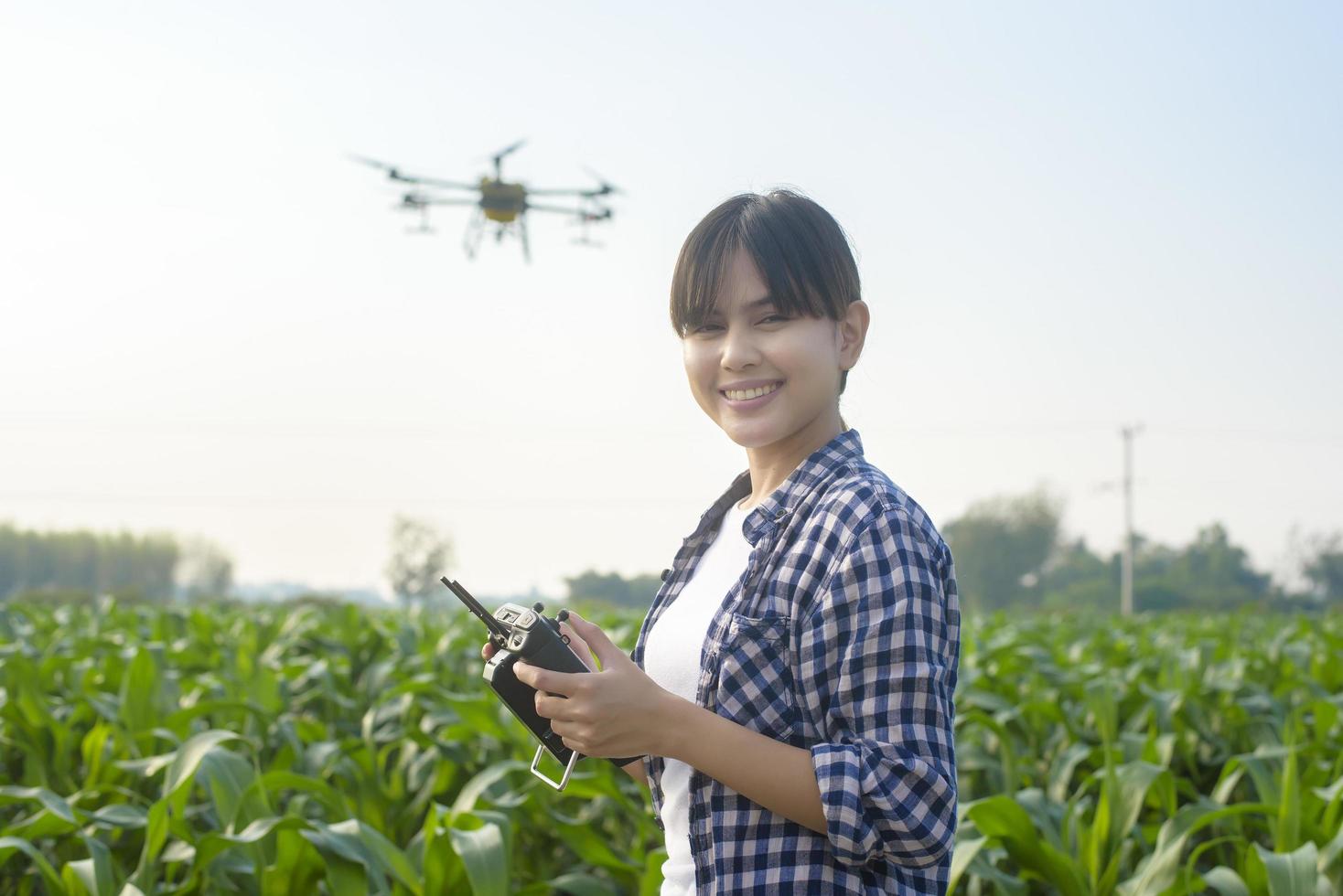 Young smart farmer controlling drone spraying fertilizer and pesticide over farmland,High technology innovations and smart farming photo