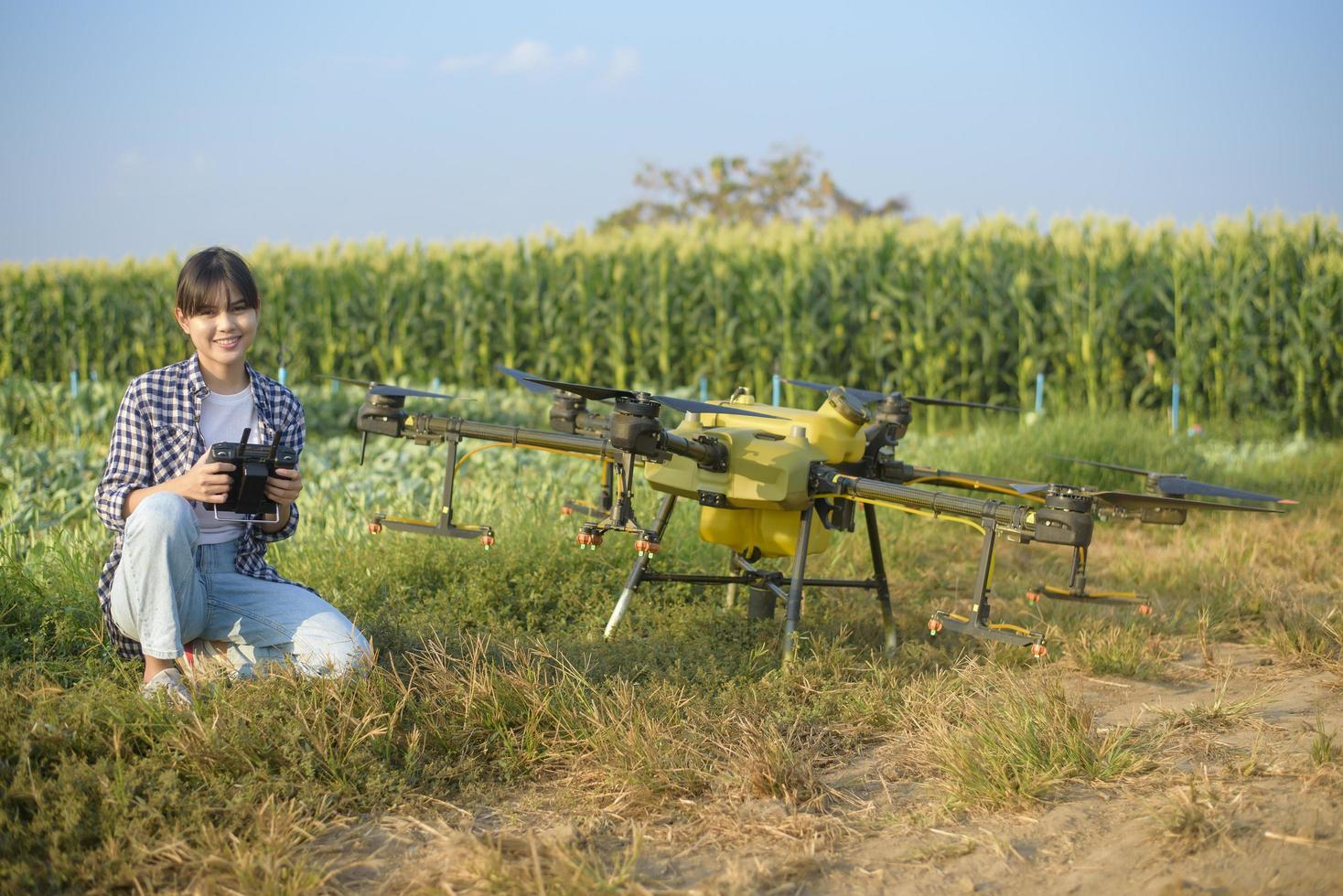 Young smart farmer controlling drone spraying fertilizer and pesticide over farmland,High technology innovations and smart farming photo