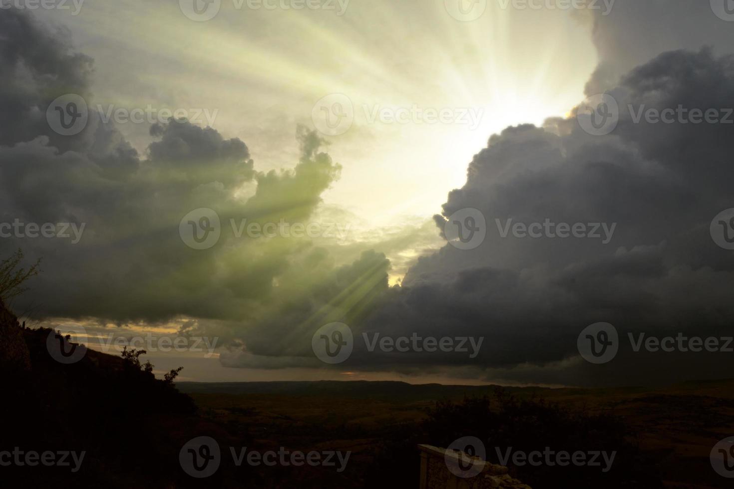 Cloudscape image of dark stormy clouds in blue sky with sun beam. The rays of the sun after the rain. Scenery with the sun's rays filtering through the gray clouds. Dramatic sky as the sun hides beh photo