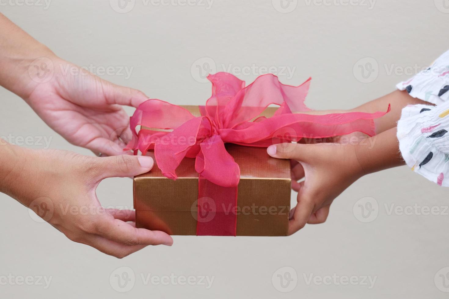 Close up of child and mother hands with gift box on white background. Holidays, present, giving, congratulations concept. New year day, Christmas day, Chinese New Year day, Birthday. photo