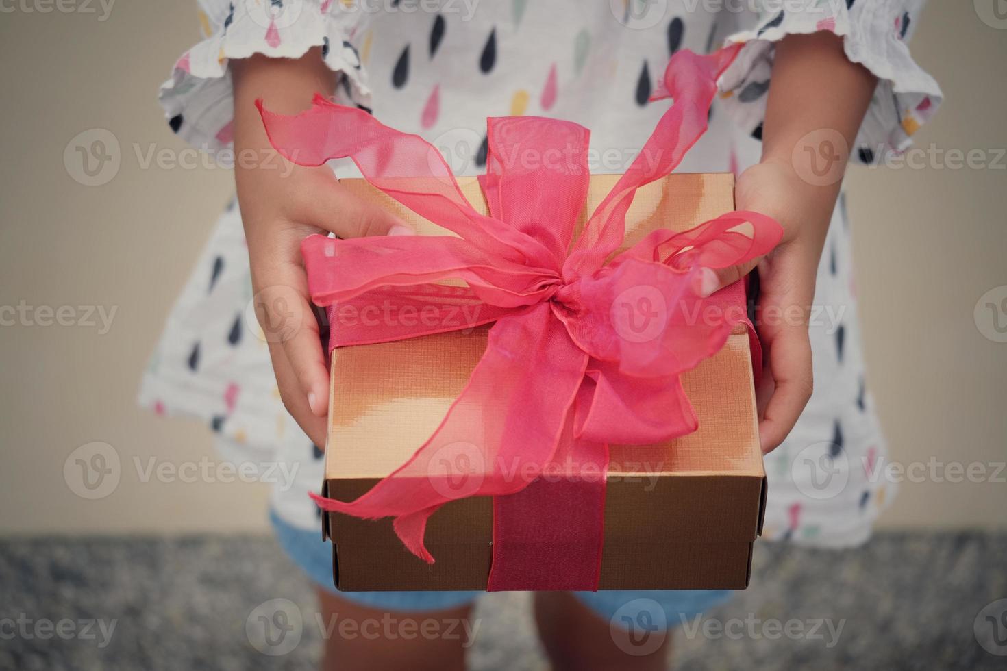 A child holds  red gift box for giving in holidays. Holidays, present, giving concept. New year day, Christmas day, Chinese New Year day, Birthday. photo