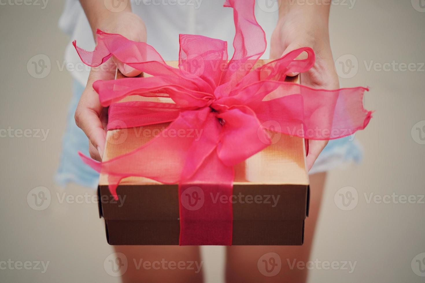 Woman holds red gift box for giving in holidays. Holidays, present, giving concept. New year day, Christmas day, Chinese New Year day, Birthday. photo