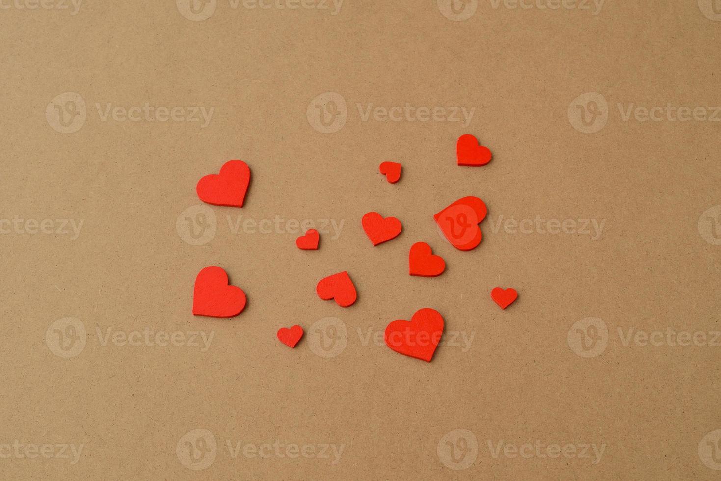 Many small wooden red hearts on a kraft paper background. Love background, Valentines day concept photo