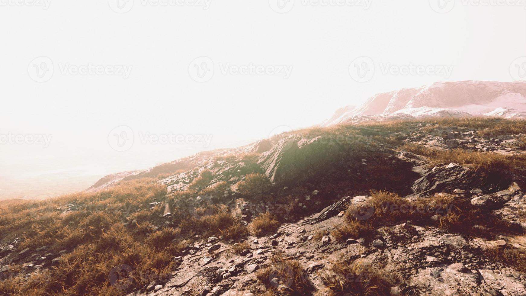 Beautiful scenic sunset view at mountain range and dry yellow grass in front photo